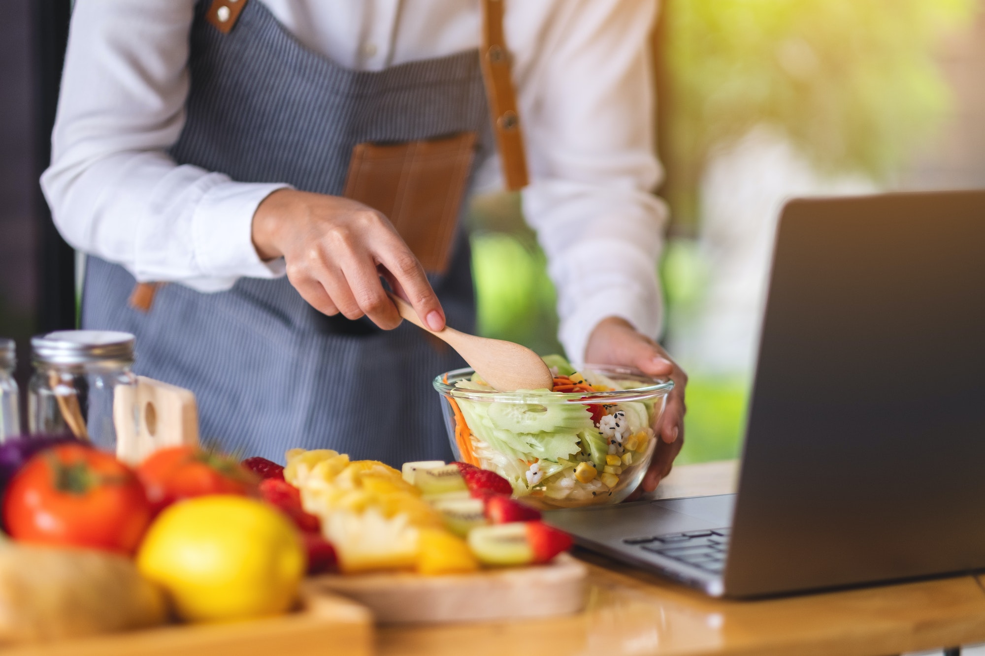 A woman videoblogger cooking in the kitchen and filming, online learning cooking class concept